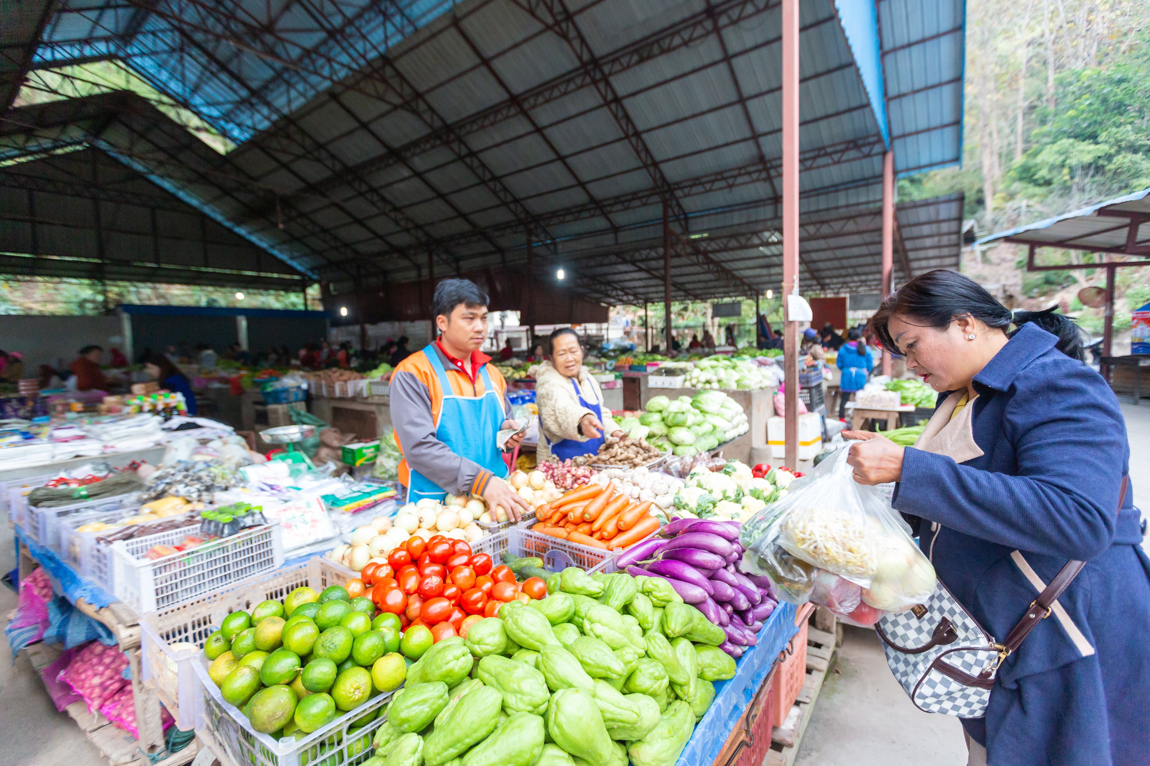 A bustling market with various fresh vegetables on display.