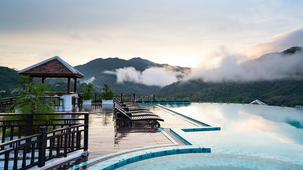 A wooden deck with a pool, a gazebo, and a mountainous backdrop. - Le Grand Pakbeng Resort (Pakbeng)