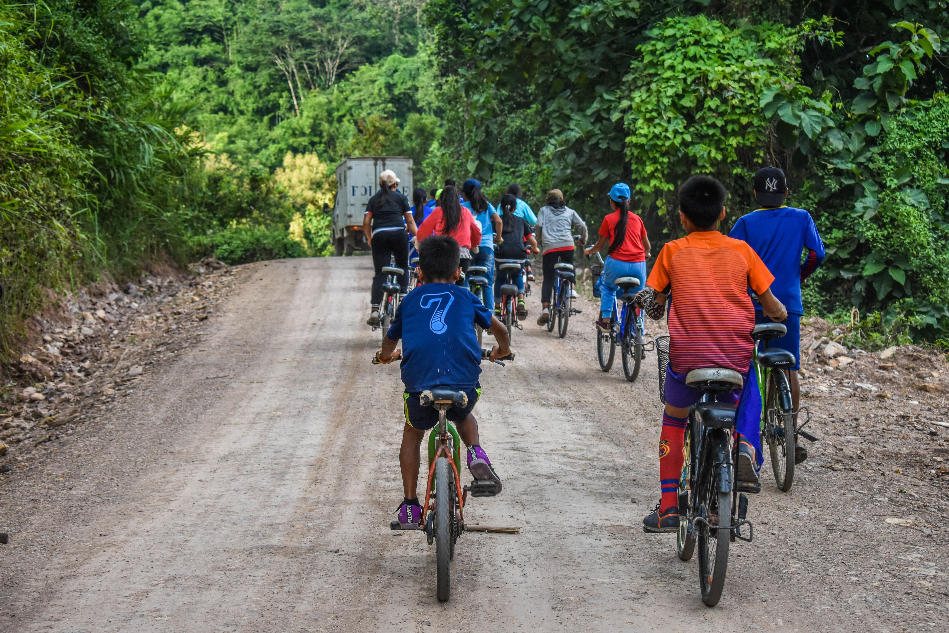 Un grupo de personas pedaleando por un camino de tierra rodeado de vegetación densa.