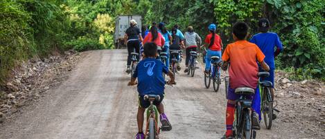 Un grupo de personas pedaleando por un camino de tierra rodeado de vegetación densa.