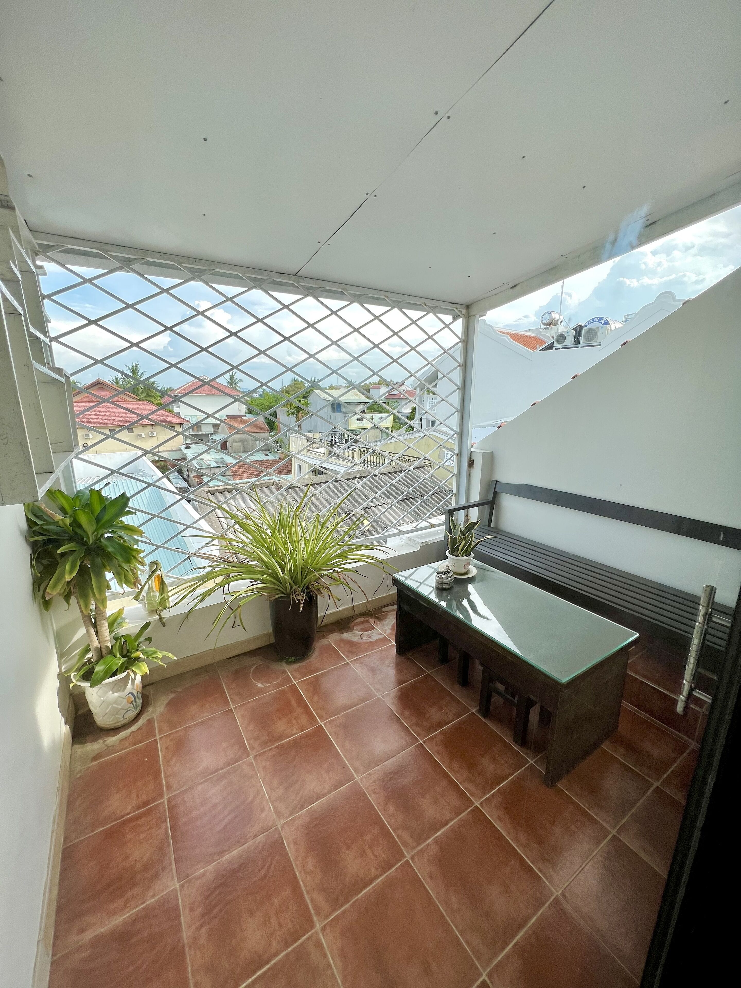 A balcony with a view of a residential area, a small table, and potted plants.