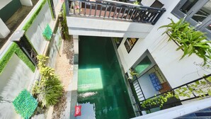 Ein modernes Gebäude mit Dachgarten, kleinem Pool und Balkon mit Geländer.