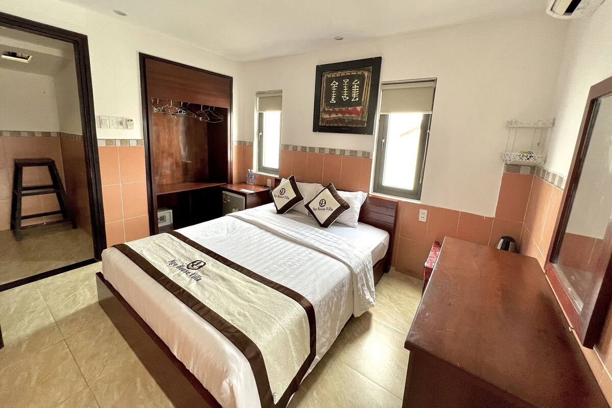A hotel room with a large bed, a wardrobe, a desk, and a mirror.