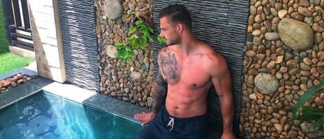 Un hombre en una piscina con un muro de piedra y una cubierta de madera.