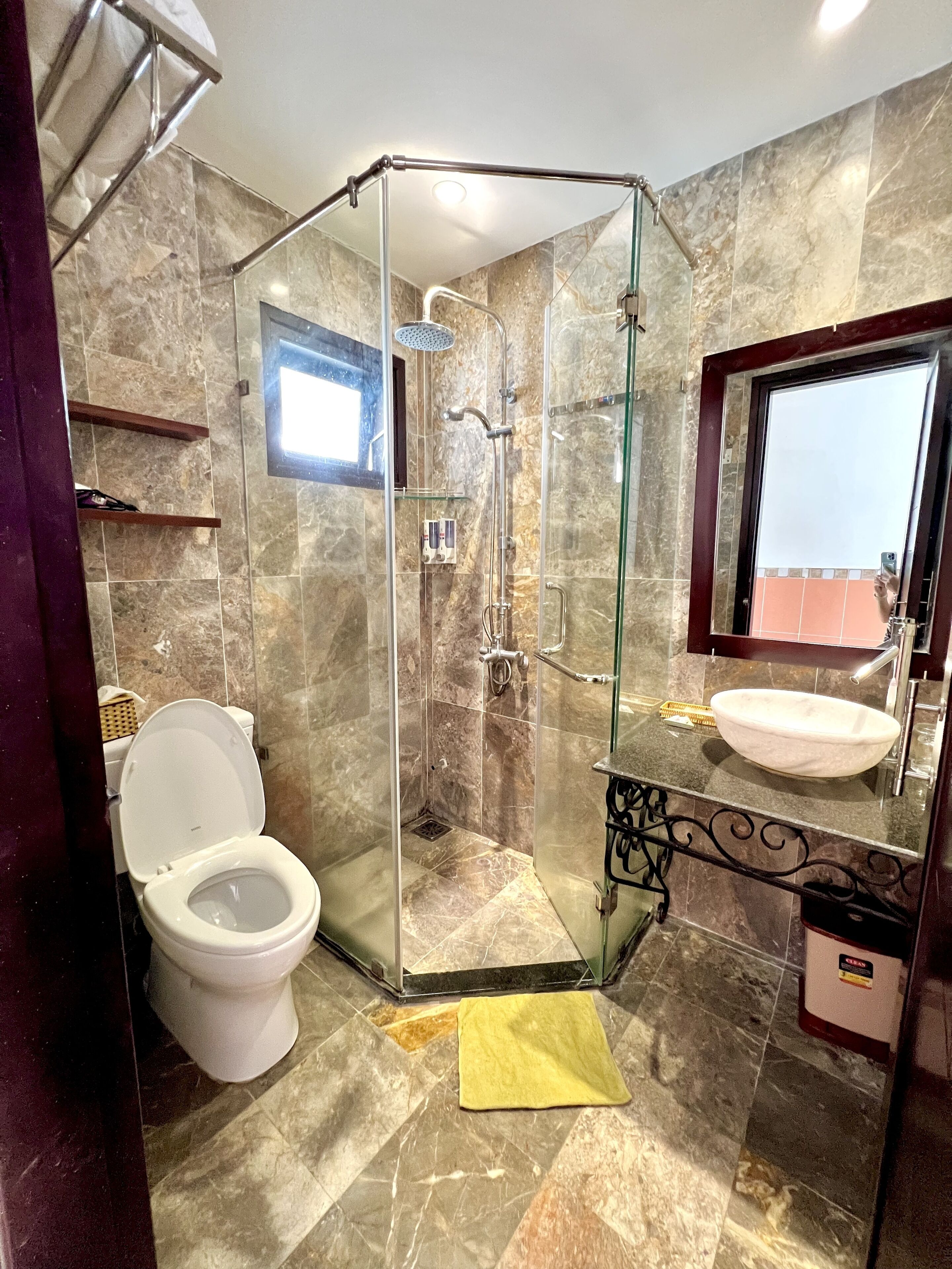 Un baño con ducha de vidrio, inodoro, lavamanos y espejo.