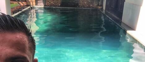 A swimming pool with clear water, stone walls, and a metal ladder.