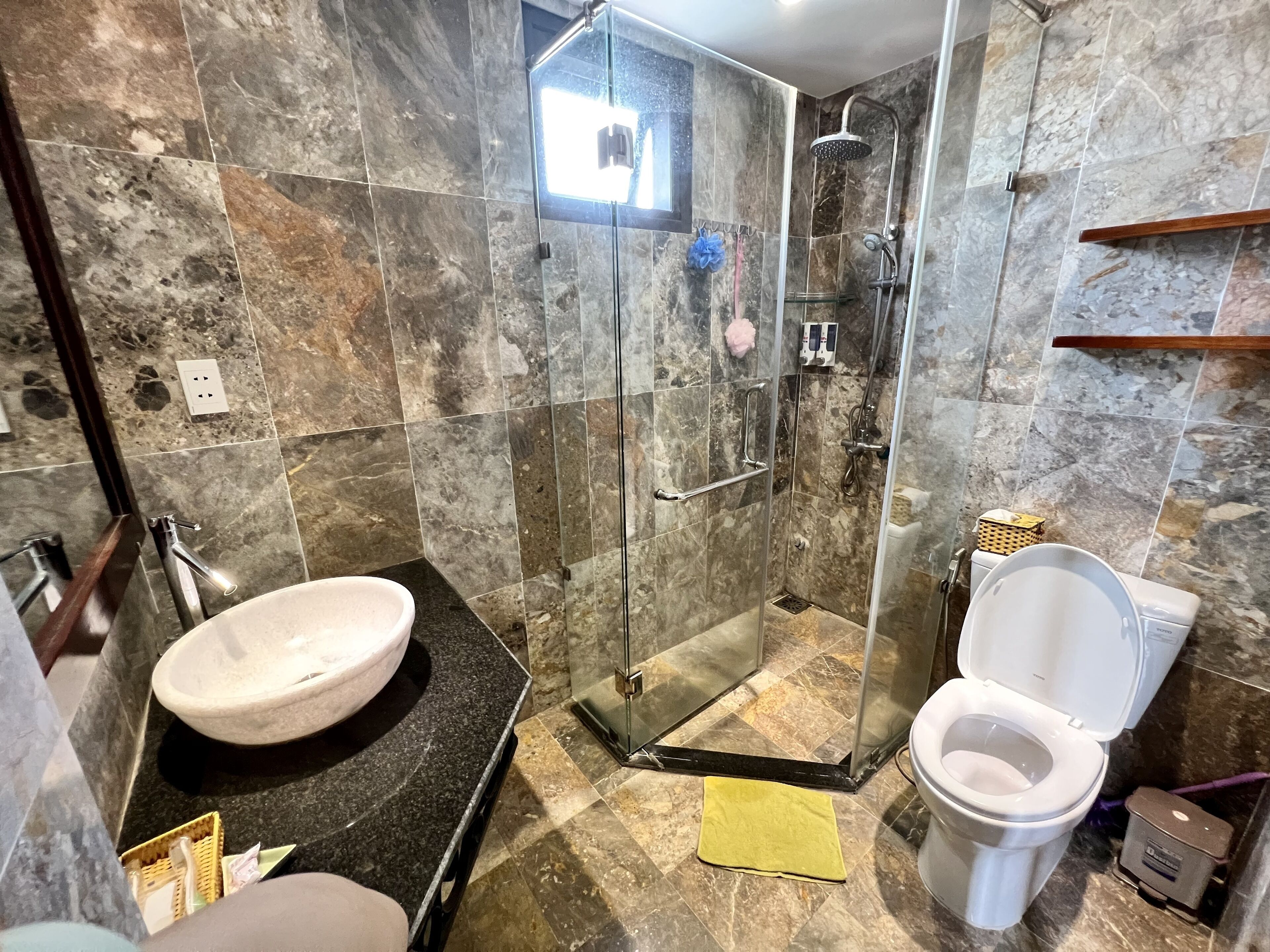 A bathroom with a glass-enclosed shower, a white sink, and a toilet.