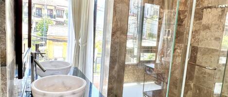 A modern bathroom with a large glass-enclosed shower, a marble countertop, and a bowl sink.