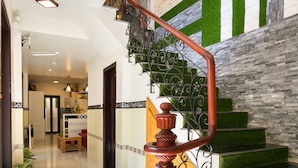 Eine moderne Treppe mit Stufen aus grünem Kunstrasen, einem Holzgeländer und einer Wand mit geometrischen Mustern.