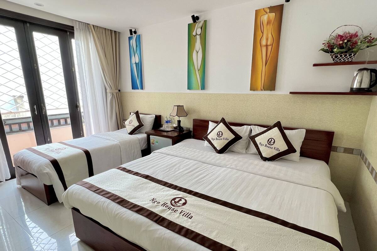 A hotel room with two beds, a nightstand, a lamp, and artwork on the wall.