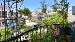 A balcony with hanging planters and a view of residential buildings. - Ngo Homestay (Da Nang)