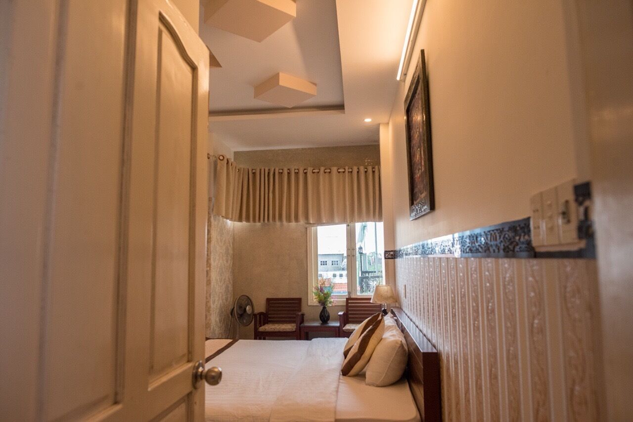 Habitación de hotel con cama, escritorio, silla, ventana con cortinas e imagen colgada en la pared.