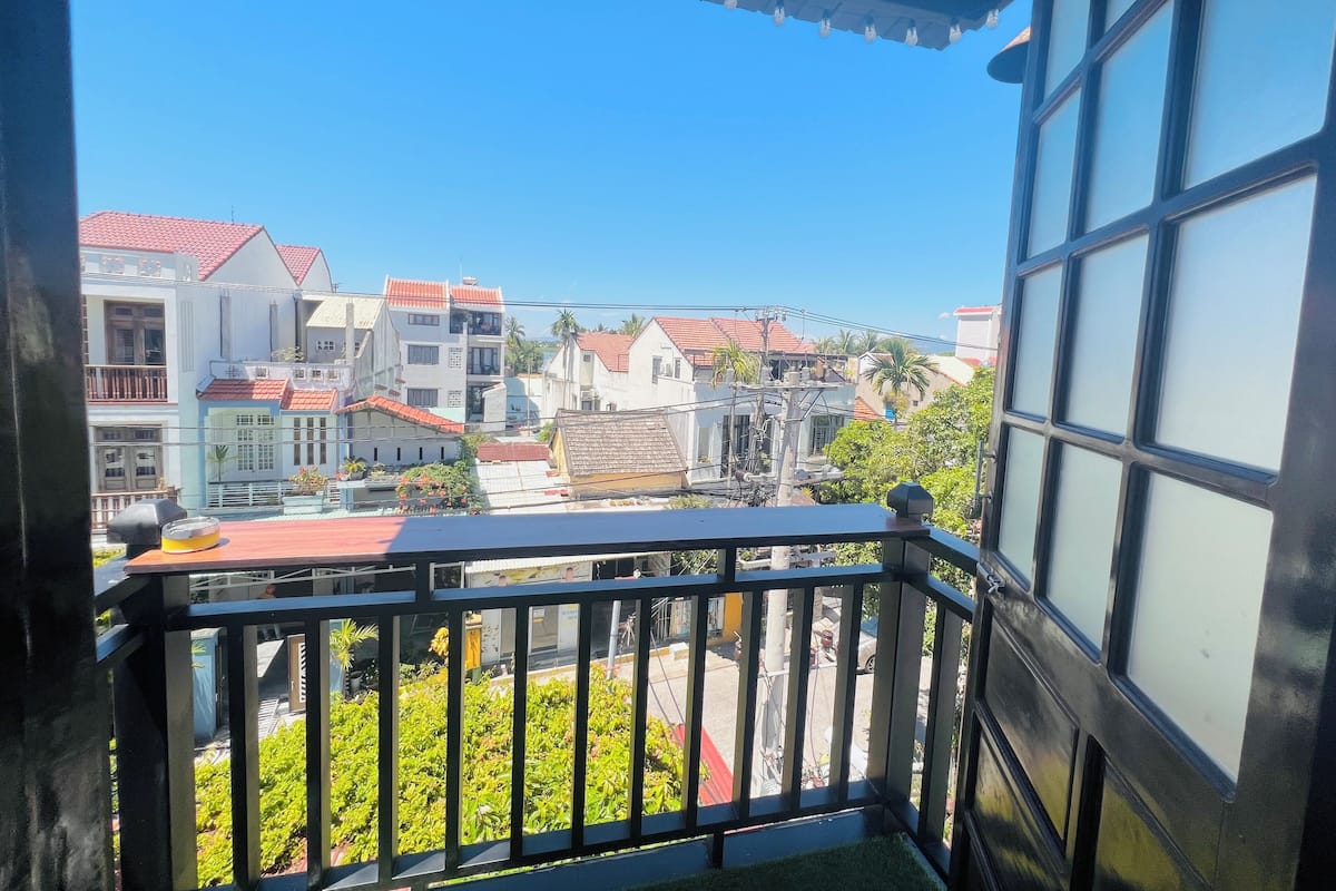 A balcony with a view of a residential area, including houses with red roofs and a clear blue sky.