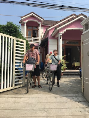 Una casa rosa con entrada protegida por una reja y un balcón.