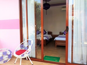 A room with two beds, a chair, and a green mat with "WELCOME" on it. - Pink House Homestay (Da Nang)