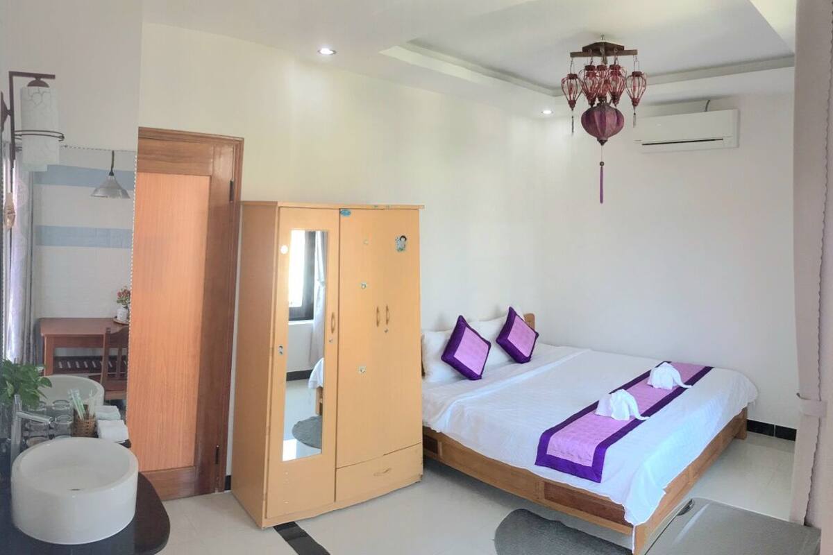 A bedroom with a bed, a wardrobe, a sink, and a ceiling light fixture.
