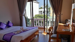 A hotel room with a bed, a desk, and a balcony. - Pink House Homestay (Da Nang)
