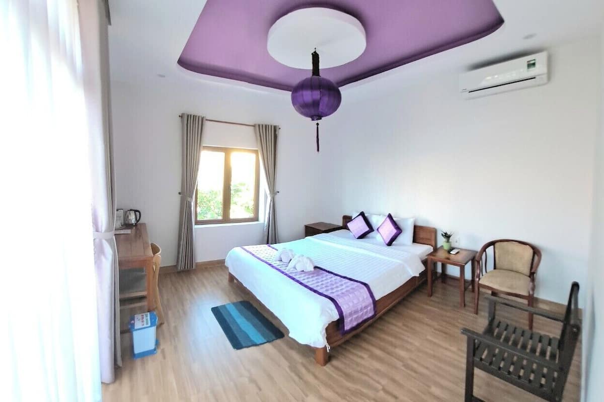 A bedroom with a bed, a chair, a desk, and a window.