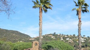 A small stone building with a single arched entrance, surrounded by palm trees and a hilly backdrop. - Studio with sleeping area near beach with parking - Le Lavandou (Le Lavandou)