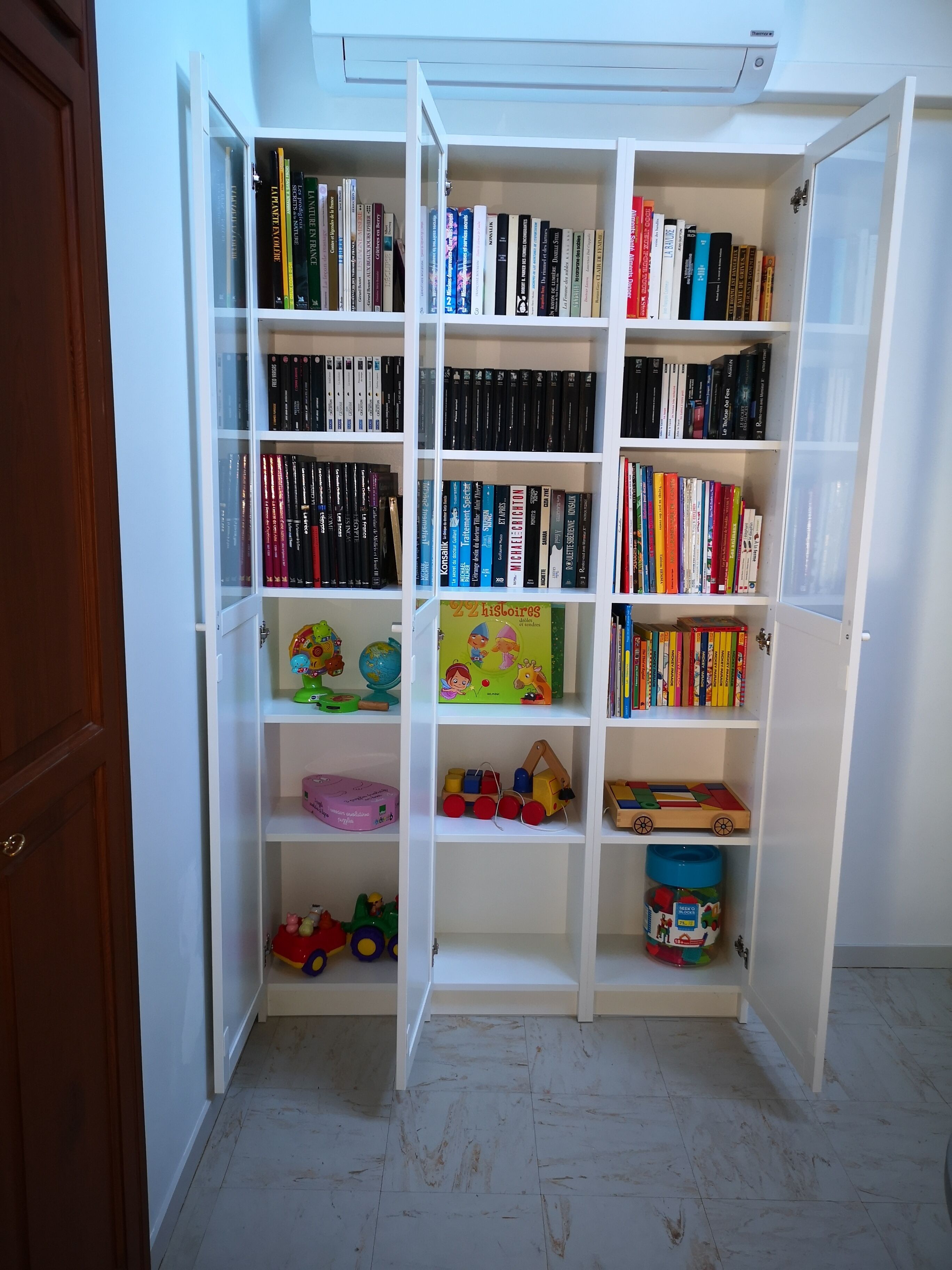 Een boekenplank met verschillende boeken en kinderspeelgoed.