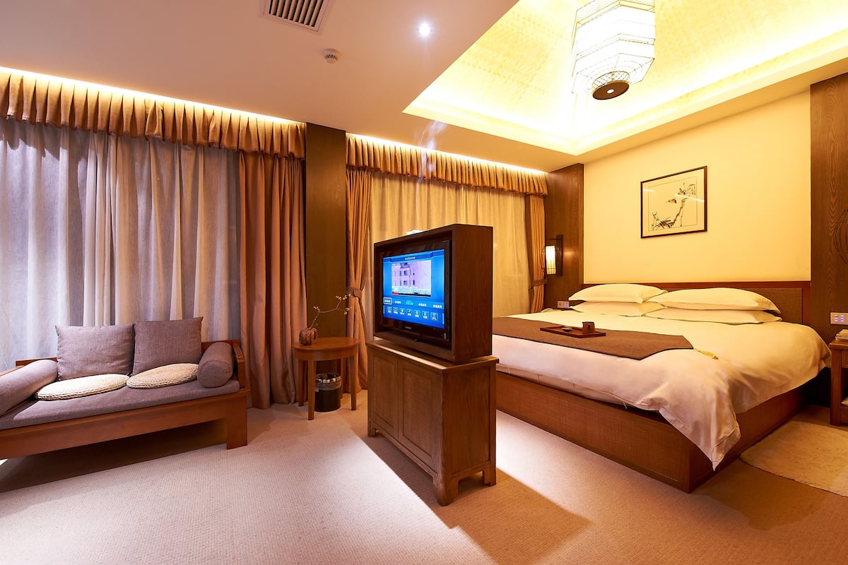 Ein Hotelzimmer mit Bett, Sofa, Fernseher und Deckenleuchte.