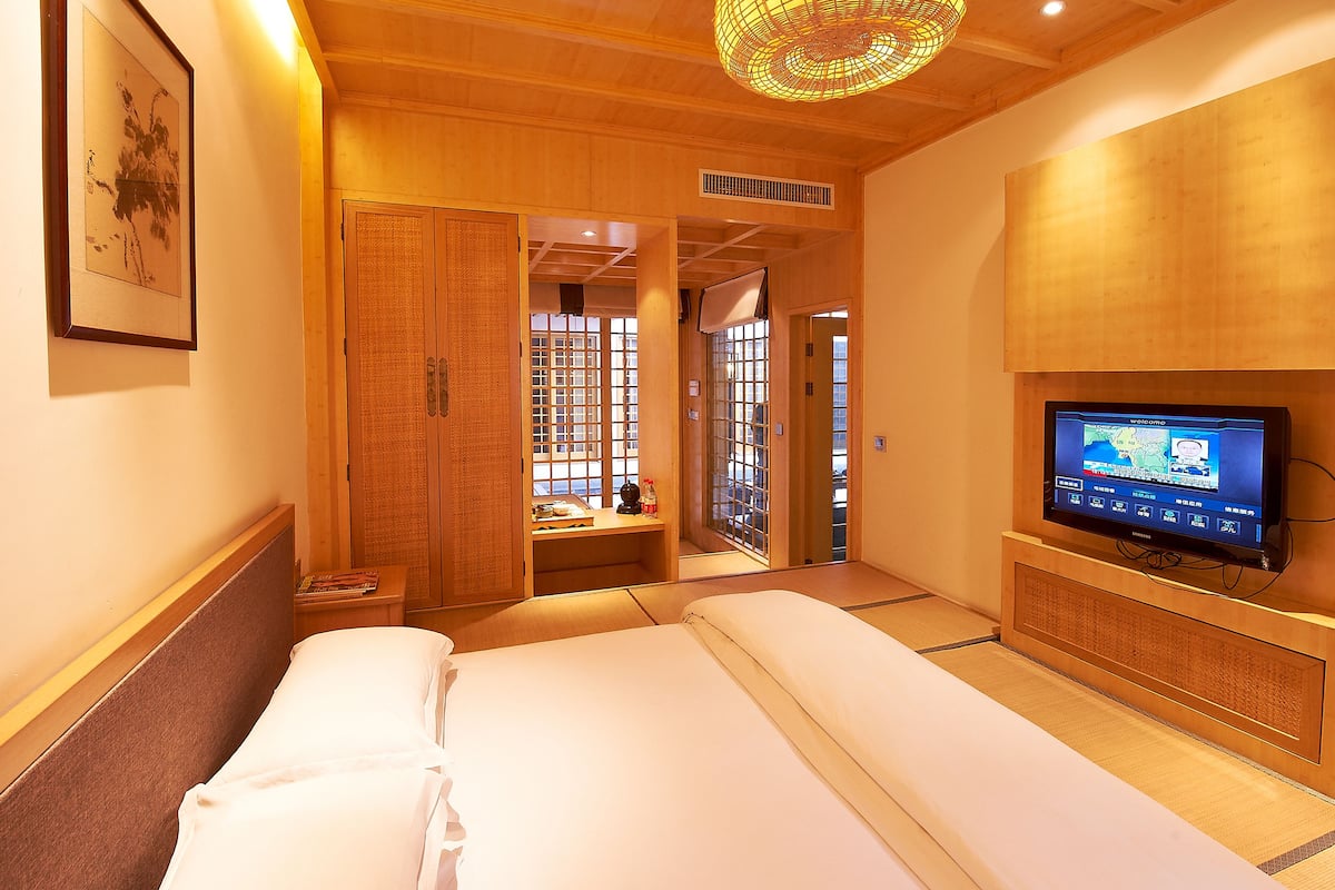 Ein Hotelzimmer mit einem Bett, einem Fernseher, einer Holzbalkendecke und einem Fenster mit Aussicht.