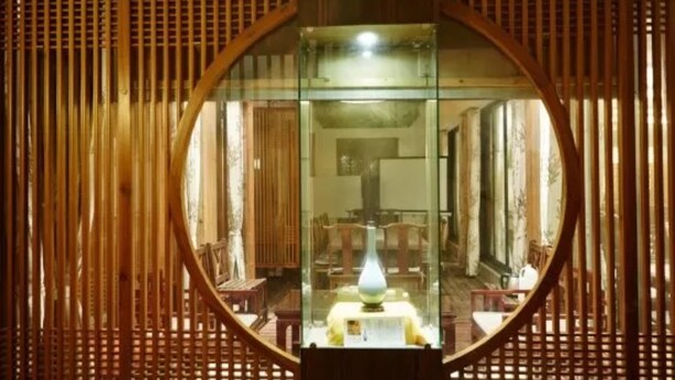 A circular mirror reflecting a room with wooden slats, a lamp, and furniture. - Xiangji Yinyu Boutique Hotel - Hangzhou (Hangzhou)