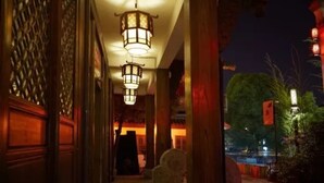A corridor with traditional wooden doors and a hanging lantern. - Xiangji Yinyu Boutique Hotel - Hangzhou (Hangzhou)