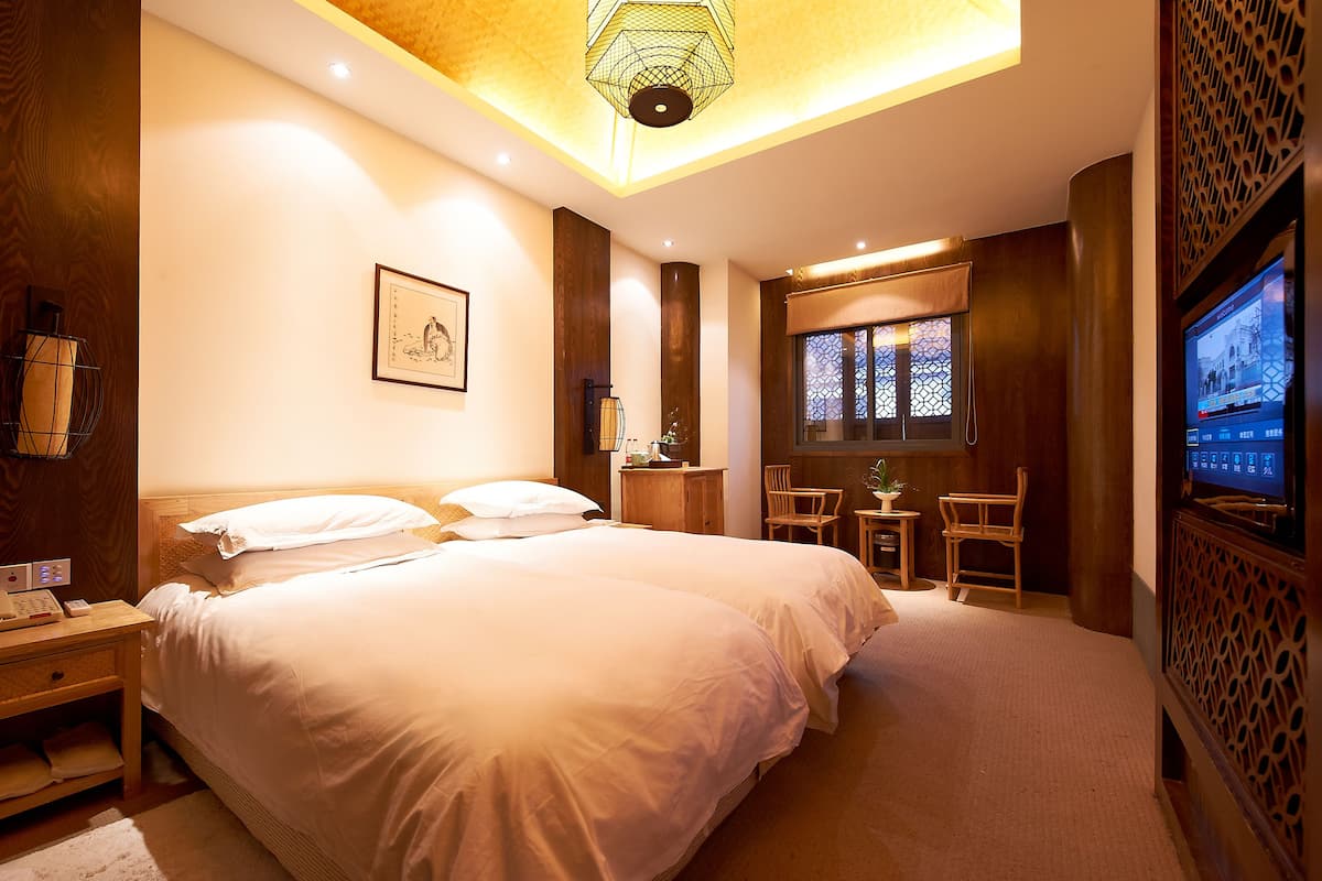 Ein Hotelzimmer mit einem großen Bett, Nachttischen, einem Schreibtisch, einem Sessel, einem Fernseher und einem Fenster mit Blick.