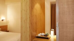 A hotel room with a wooden ceiling, a bed, a nightstand, and a small table with tea set. - Xiangji Yinyu Boutique Hotel - Hangzhou (Hangzhou)