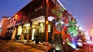 A traditional building with a sloped roof and a balcony, surrounded by potted plants and a stone pathway. - Xiangji Yinyu Boutique Hotel - Hangzhou (Hangzhou)