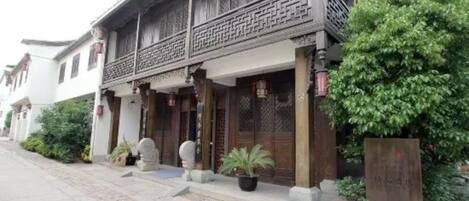 A traditional building with a wooden balcony, stone lanterns, and potted plants.