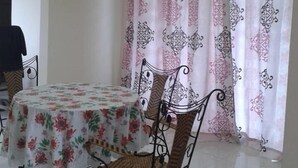 A dining area with a table covered in a floral tablecloth, surrounded by wicker chairs. - HomeStay RoomStay Klebang Melaka (Malacca City)