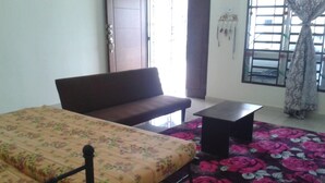 A room with a bed, a sofa, a small table, and a window with curtains. - HomeStay RoomStay Klebang Melaka (Malacca City)