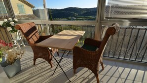 Ein Balkon mit Korbmöbeln, einem Tisch und Stühlen mit Blick auf eine malerische Landschaft.