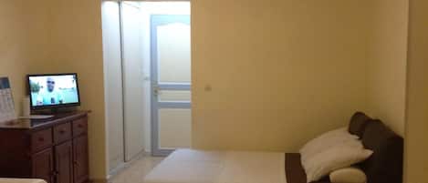 A bedroom with a bed, a desk, a chair, and a television.