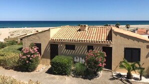 Un bâtiment doté d’un toit en tuiles, entouré de verdure et offrant une vue sur la plage.