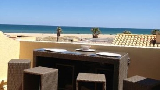 Une terrasse sur le toit offrant une vue sur la plage, avec des meubles en osier et une table dressée.