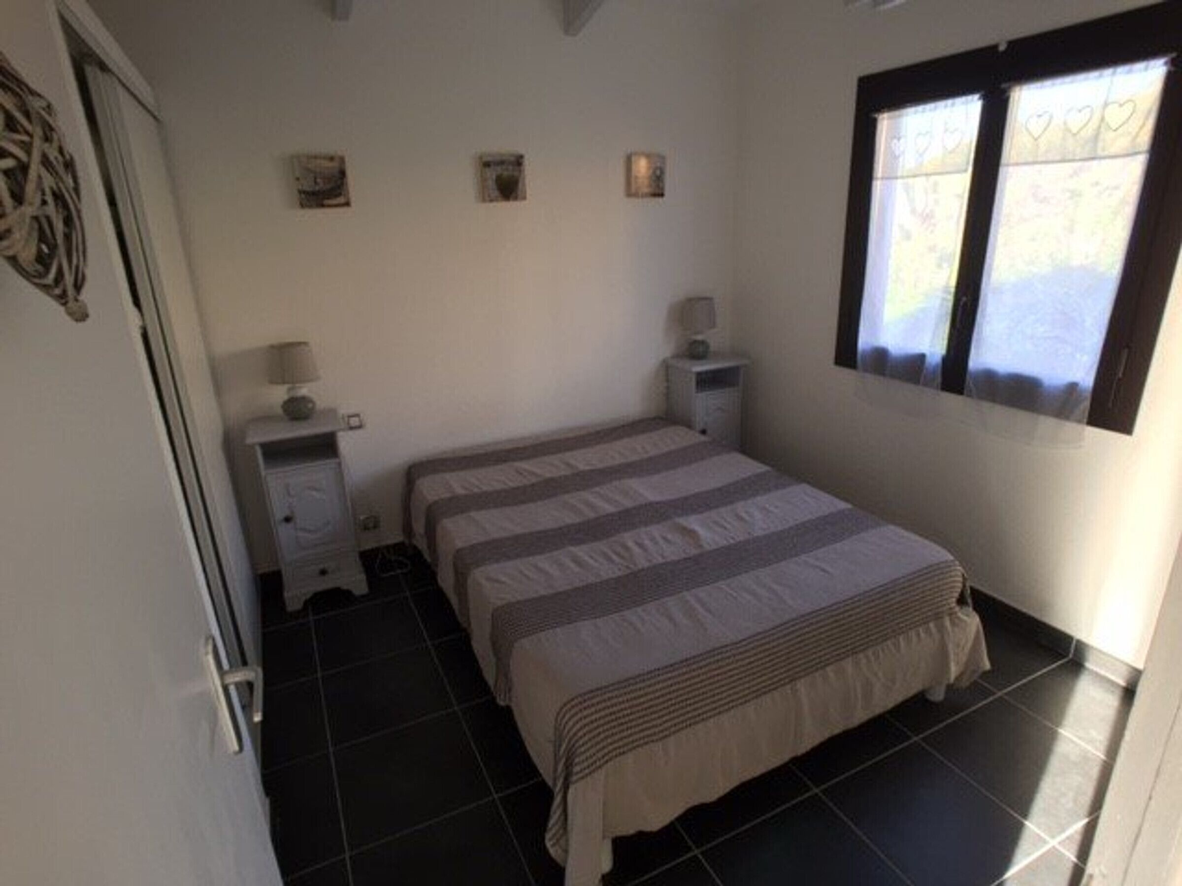 Een slaapkamer met een bed, twee nachtkastjes, een raam met gordijnen.