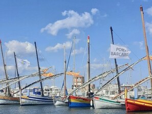 Satamassa oli useita laivoja kiinnitettynä laitureihin, taivas oli kirkas ja siellä oli kyltti, jossa luki: ’PORT BARCARE’.
