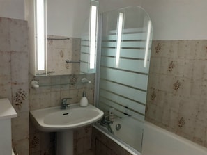 A bathroom with a sink, mirror, and shower.