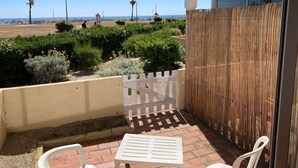 A balcony with a view of the beach, a white table, and a white chair. - Seaside studio for 3 pers with parking (Port Leucate)