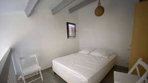 A bedroom with a bed, a chair, and a small picture frame on the wall.