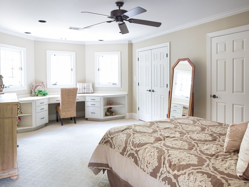 Quarto com cama, escrivaninha, cadeira, guarda-roupa e ventoinha no teto.