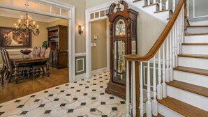 Un'imponente scala con balaustre bianche e corrimano in legno, che conduce a un piano superiore.