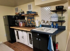 A compact kitchen with a refrigerator, microwave, stove, sink, and cabinets.