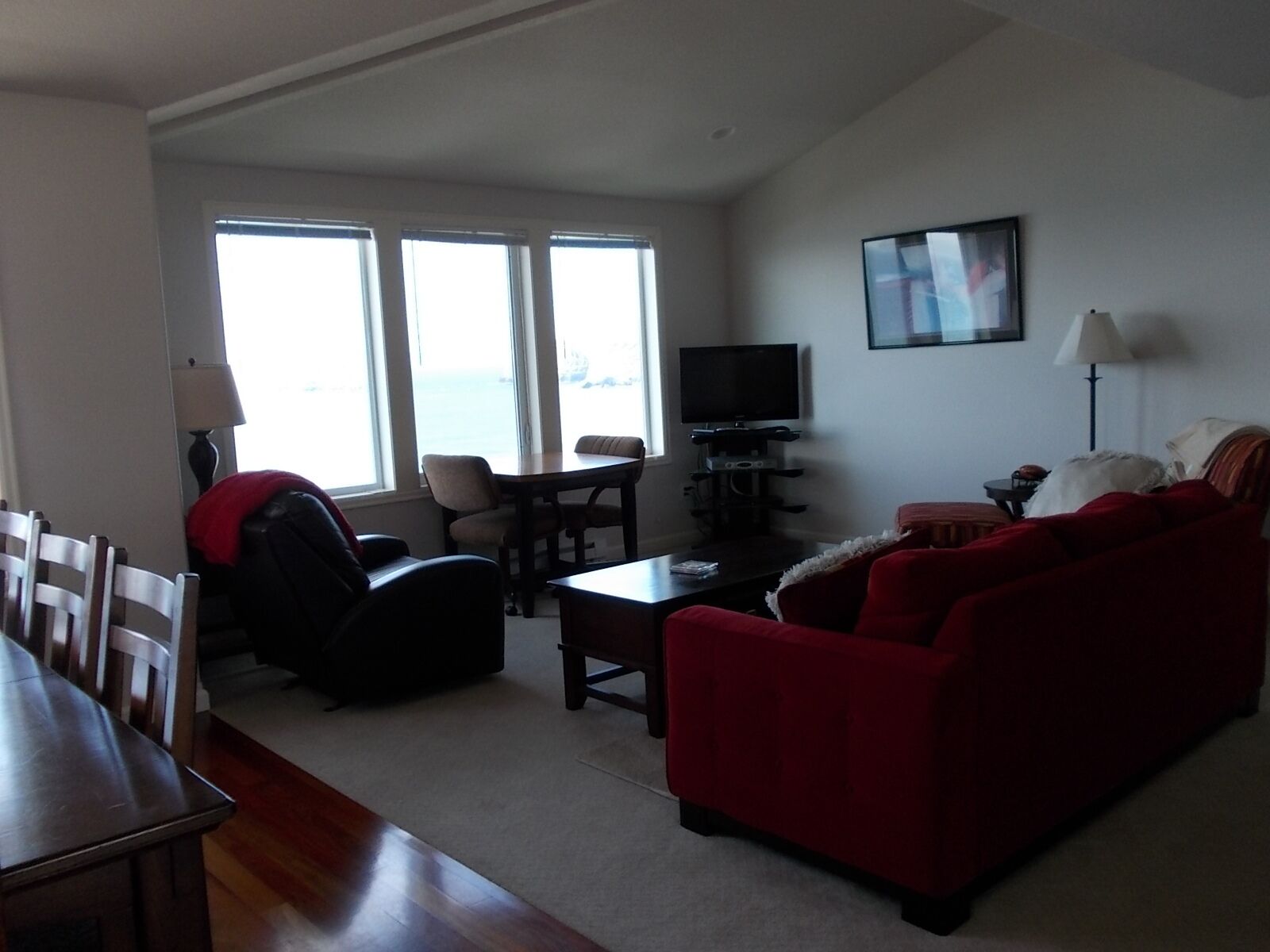 A living room with a red sofa, a TV, and a dining area with a table and chairs.