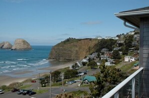 Uma vila costeira com praia, falésias rochosas e edifícios residenciais.