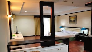 A hotel room with a bed, bedside tables, a desk, a chair, a sofa, and a large mirror. - PIH Batam (Batam)