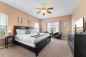 A bedroom with a bed, bedside tables, a dresser, a ceiling fan, and artwork on the walls. - Spacious Lake Front Condo, Sunsets, 5 min to SDC (Branson)